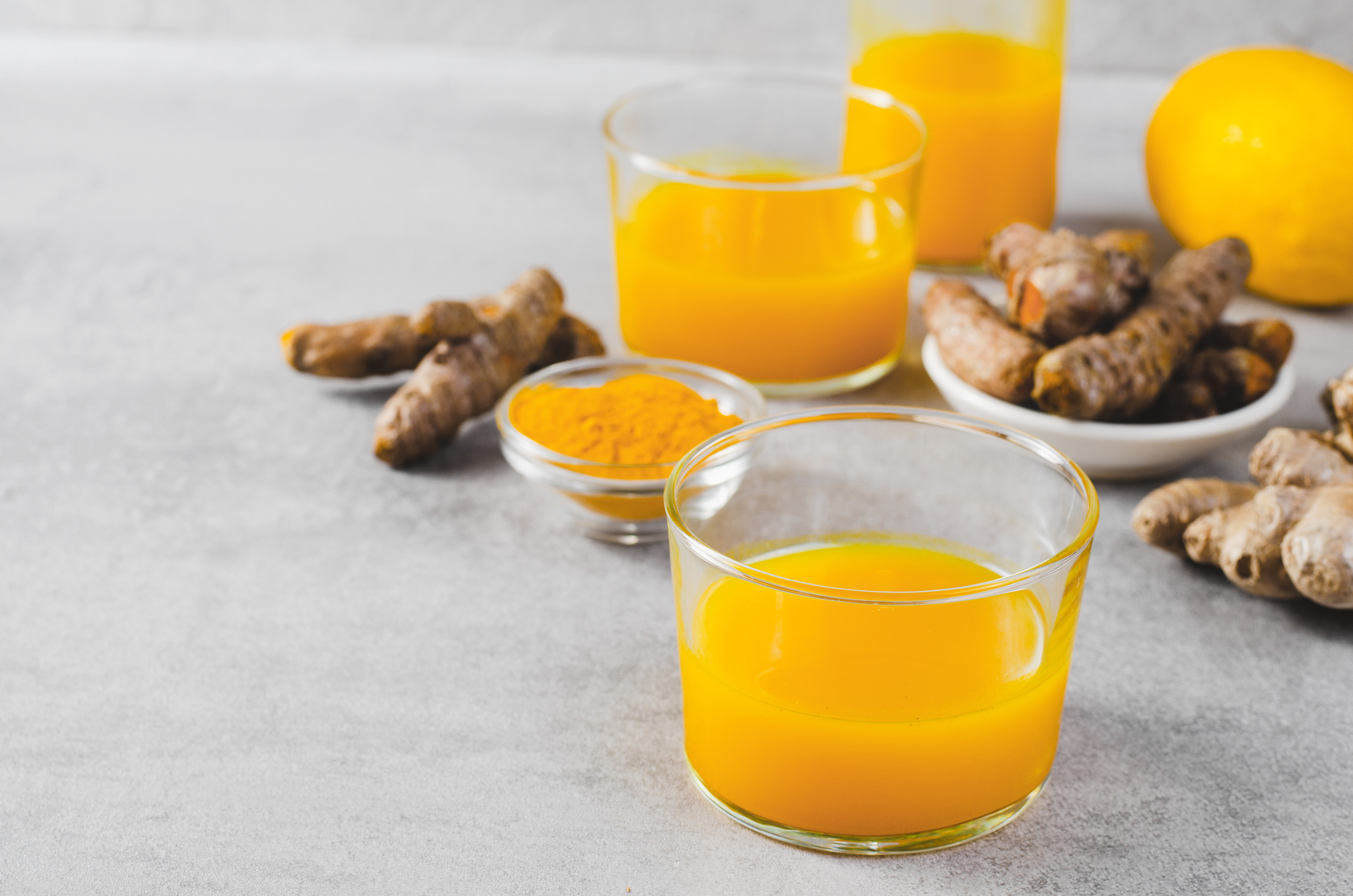 Turmeric Shots, Healthy Beverage with Turmeric Root and Spices, Jamu Juice, Immunity Booster Drink on Grey Background